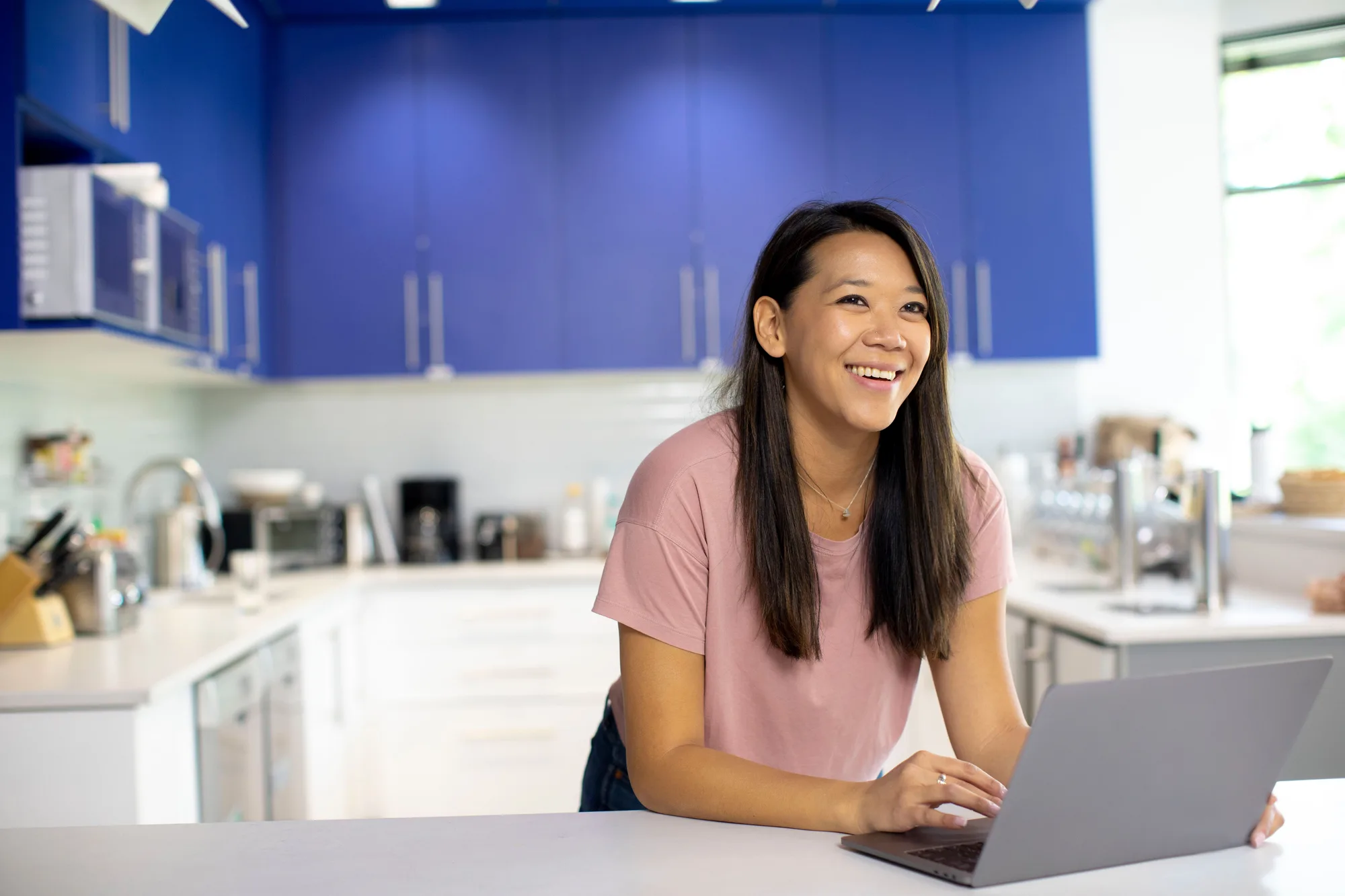 Woman holding a drink while seated next to a laptop